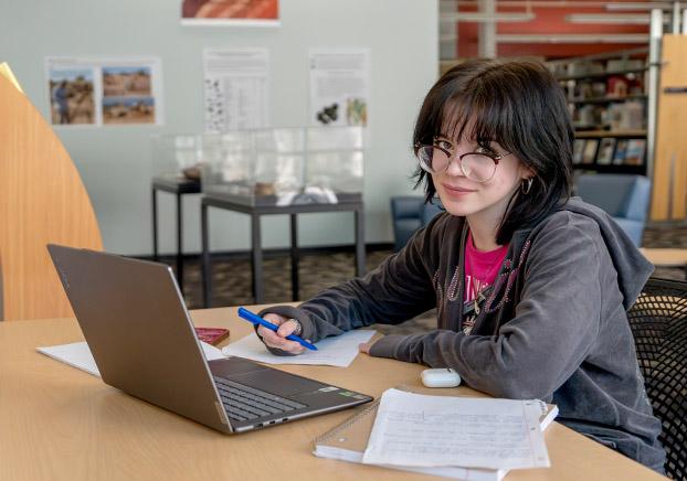 An ACE student sitting at a desk working on her laptop and doing homework